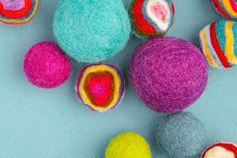Colorful felt balls on a blue background representing Arts & Craft programs